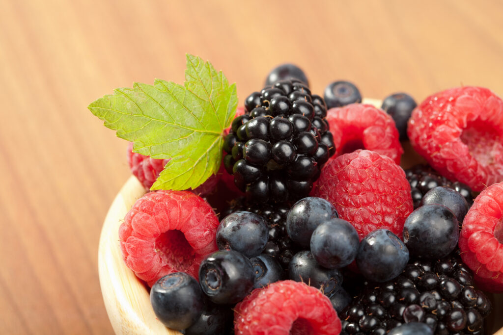 raspberries, blackberries and blueberries in a wooden bowl.