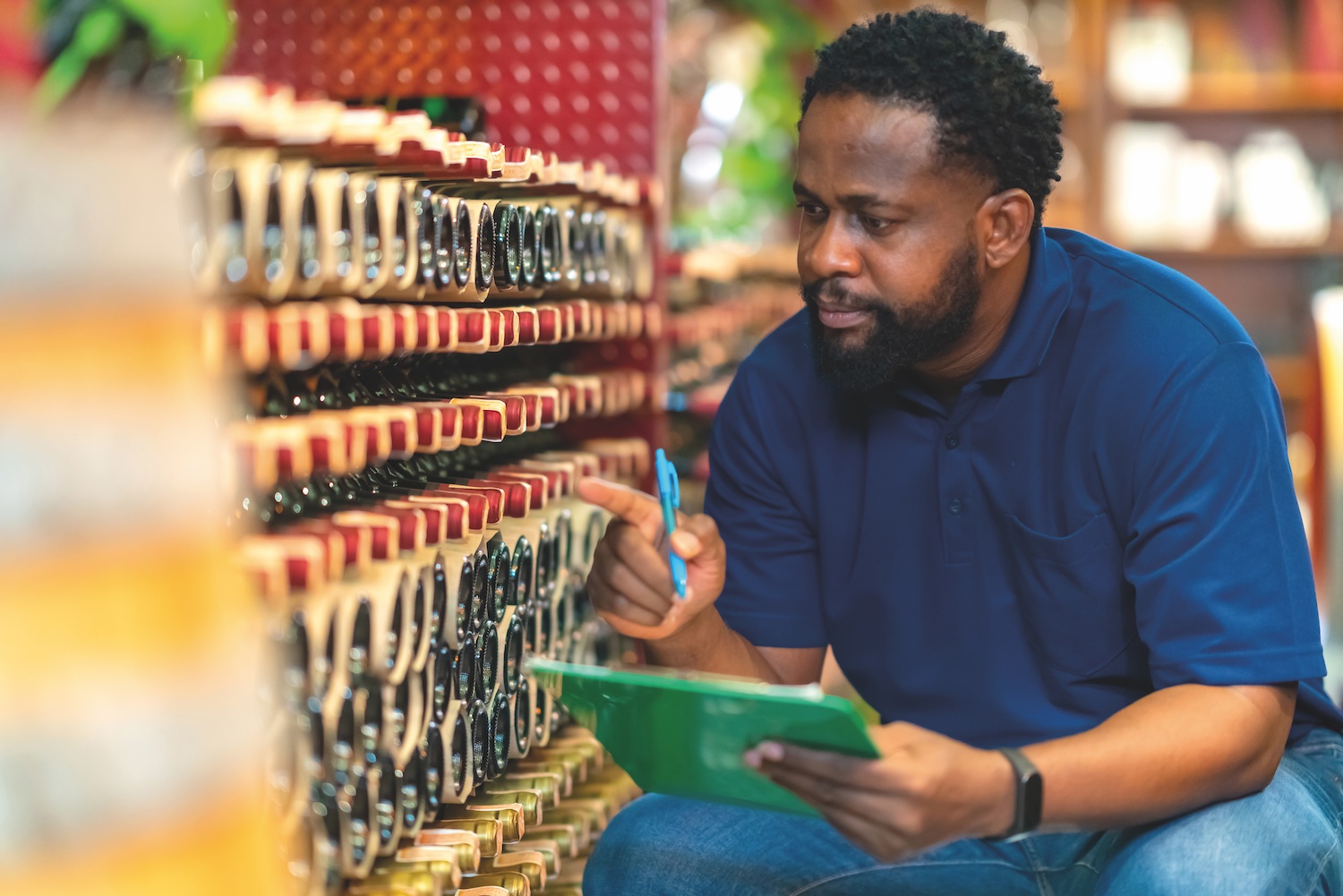 Photo of a distribution worker counting bottles of alcohol on a shelf in a warehouse.