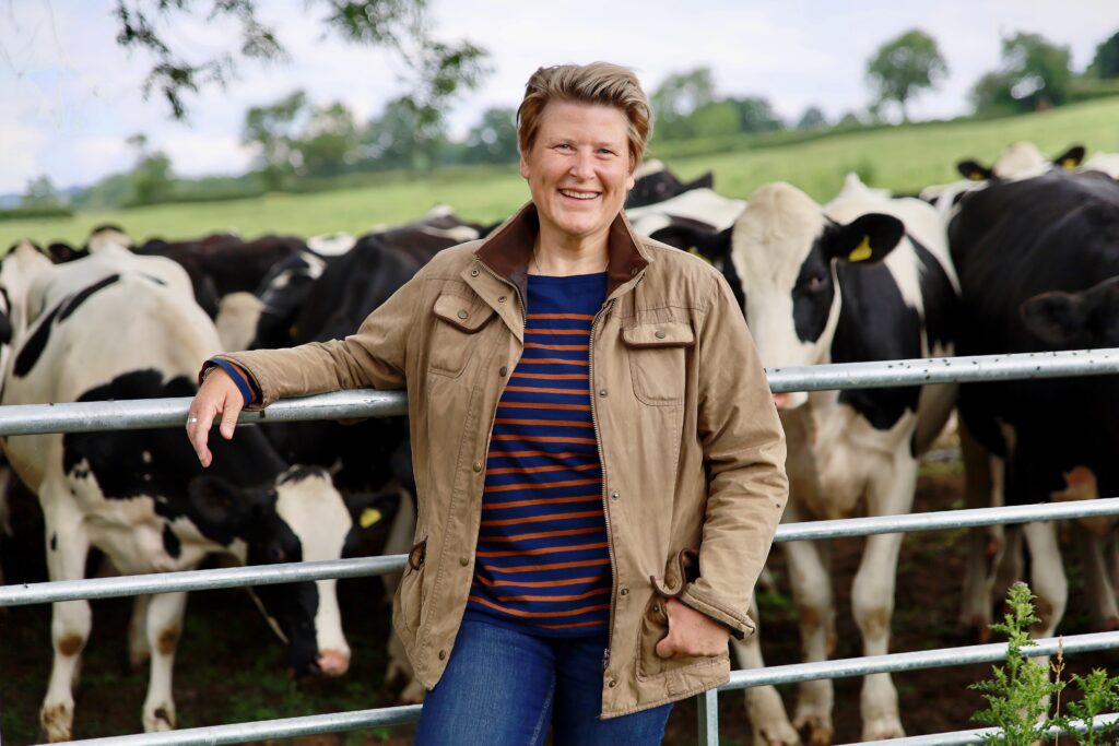 Sarak Dyke MP Lib Dems standing by cows in a farm