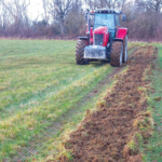 Tractor in field planting new vines