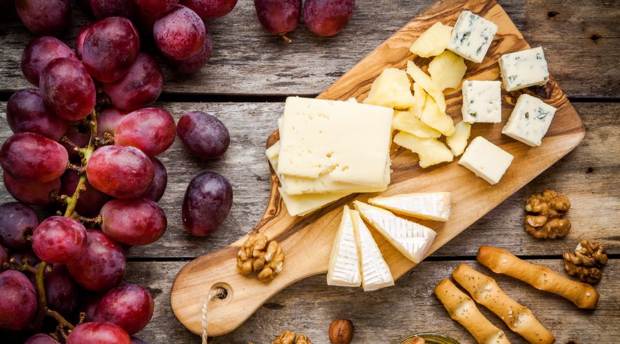 Cheese board and grapes with crackers on wooden board